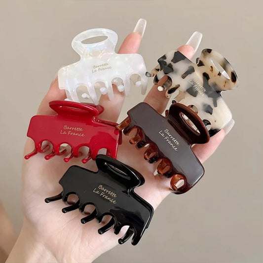 femme tient pince a cheveux noir blanc brun rouge léopard